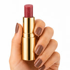 Gold lipstick case with red lipstick held by a hand on a white background