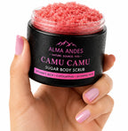 Hand holding a jar of Alma Andes Camu Camu Sugar Body Scrub with pink scrub visible.